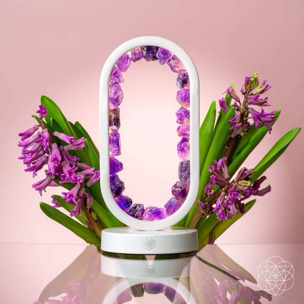 Amethyst crystal arch lamp styled with purple flowers on a pink background