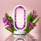 Amethyst crystal arch lamp styled with purple flowers on a pink background