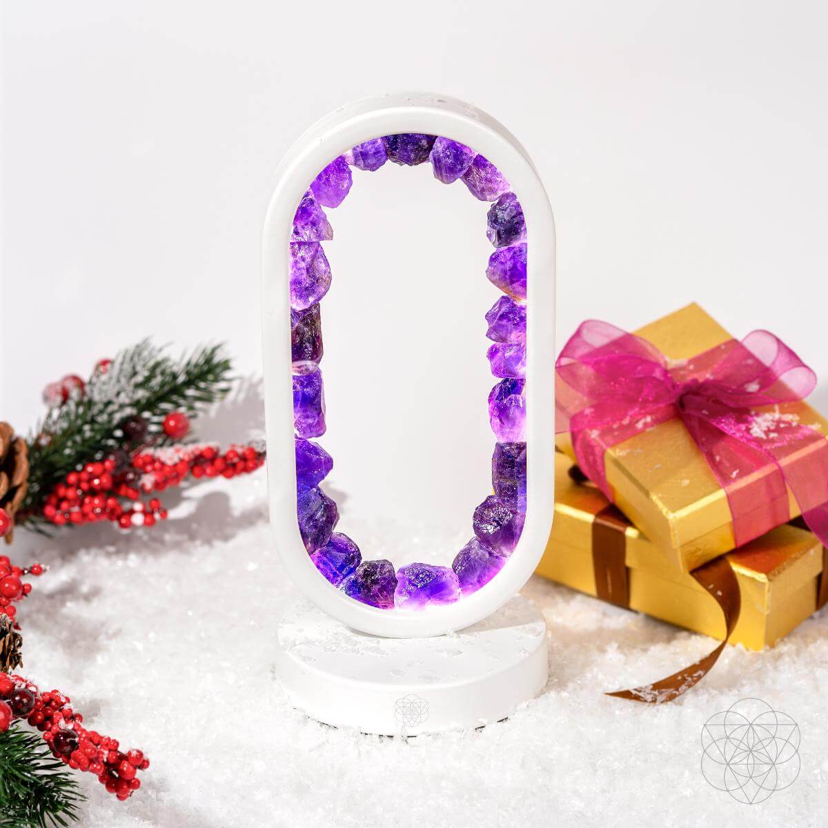 Glowing amethyst crystal arch lamp beside holiday greenery and gift boxes