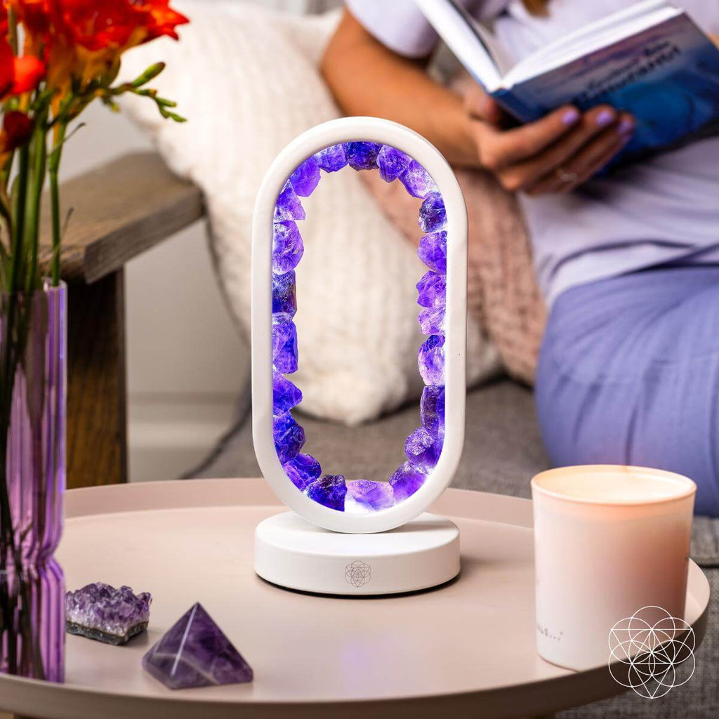 Amethyst crystal arch lamp glowing on a bedside table while a person reads