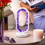 Amethyst crystal arch lamp glowing on a bedside table while a person reads